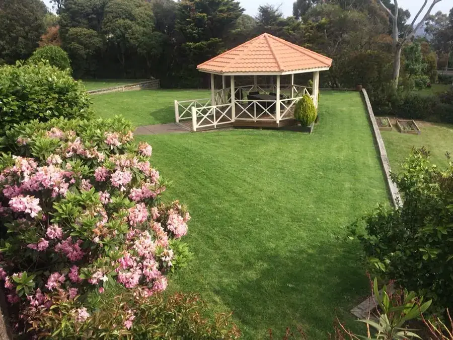 Mowed garden lawn surrounding a gazebo and flowering shrubs